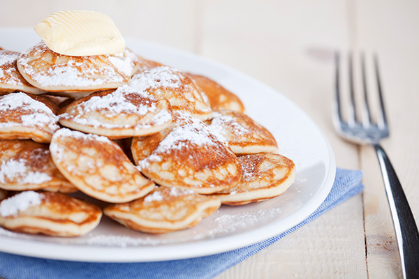 Poffertjes met poedersuiker en een vork ernaast