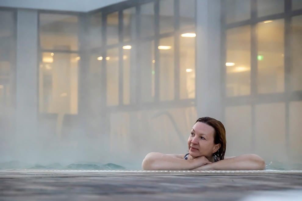 vrouw die naar links kijkt terwijl ze zich in een dampend bad bevindt