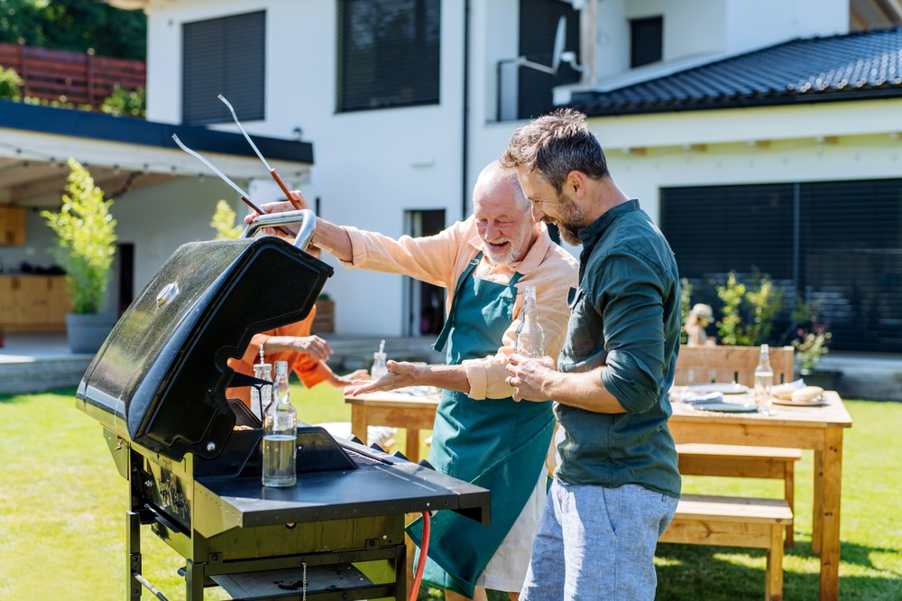 Vader en zoon in de tuin bij de barbecue